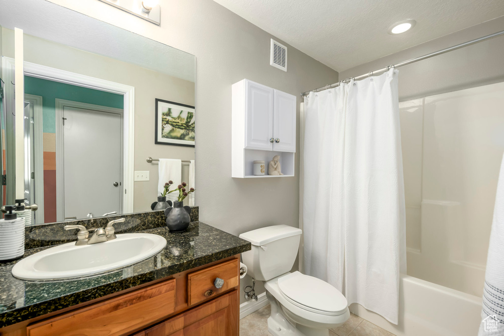 Bathroom featuring toilet, tile patterned flooring, vanity, and shower / bath combo with shower curtain