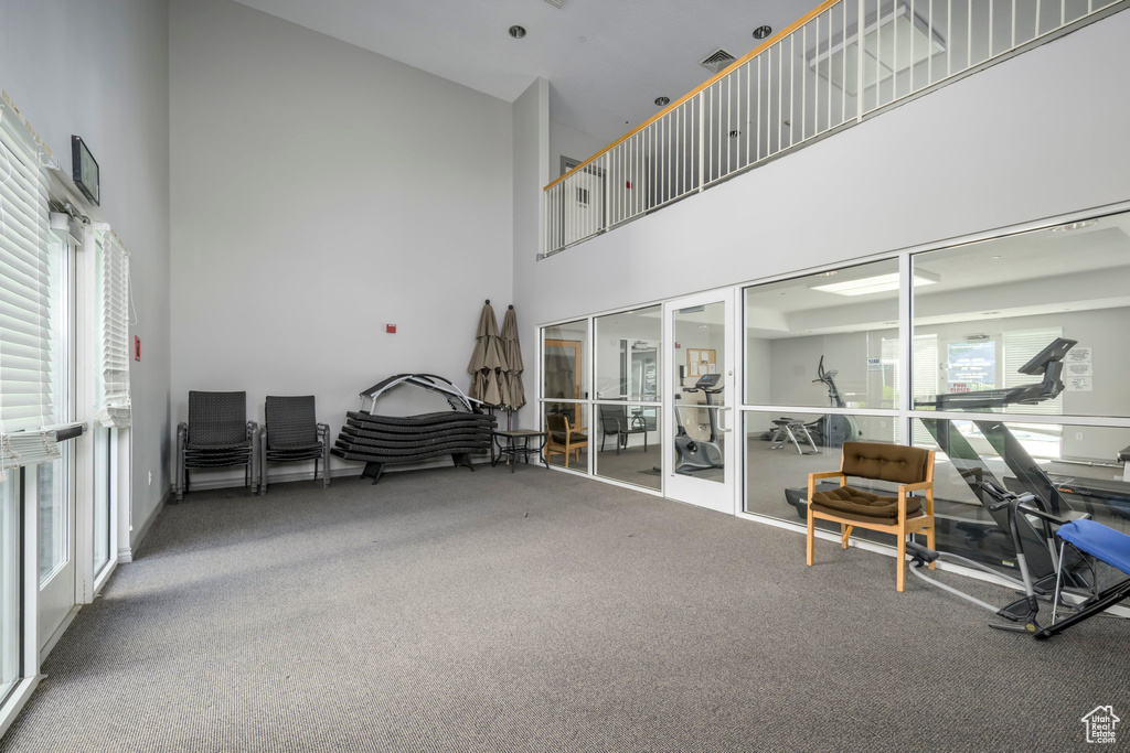 Living area featuring a high ceiling, french doors, carpet flooring, and a desk