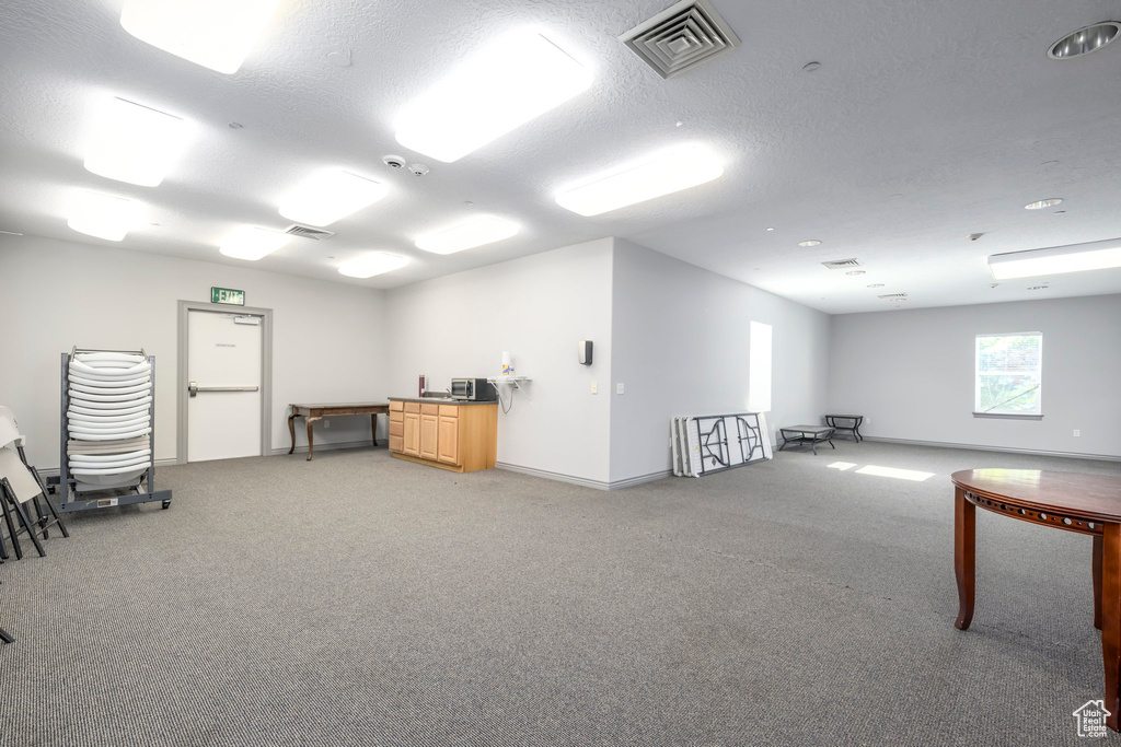 Miscellaneous room featuring light carpet, a textured ceiling, and baseboards