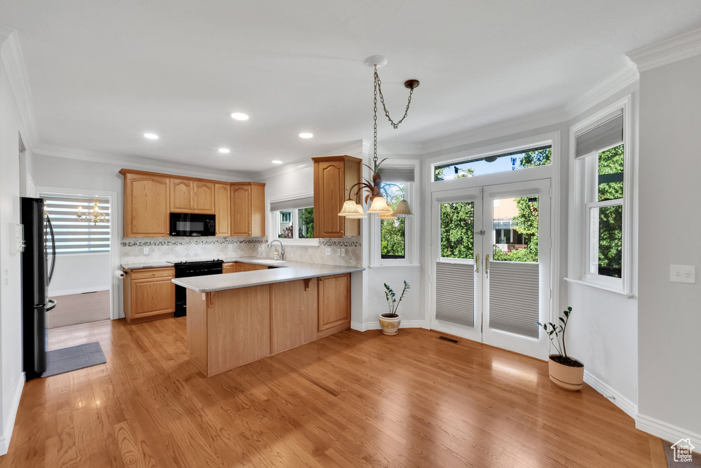 Kitchen featuring black appliances, a sink, plenty of natural light, ornamental molding, and recessed lighting