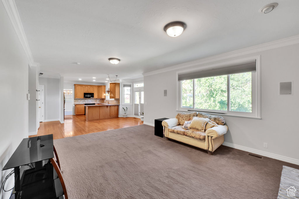 Living room with ornamental molding, light colored carpet, baseboards, and recessed lighting