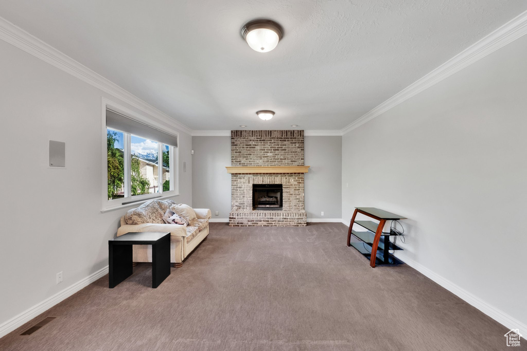 Carpeted living room with crown molding, a fireplace, and baseboards