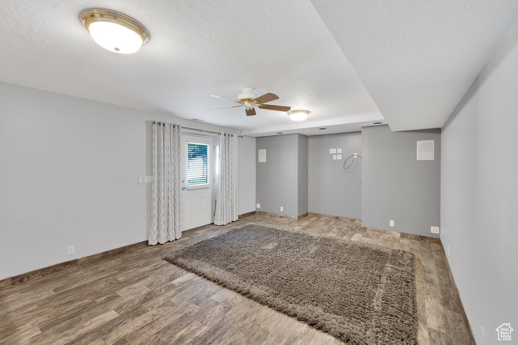 Unfurnished room with a ceiling fan, wood finished floors, and baseboards