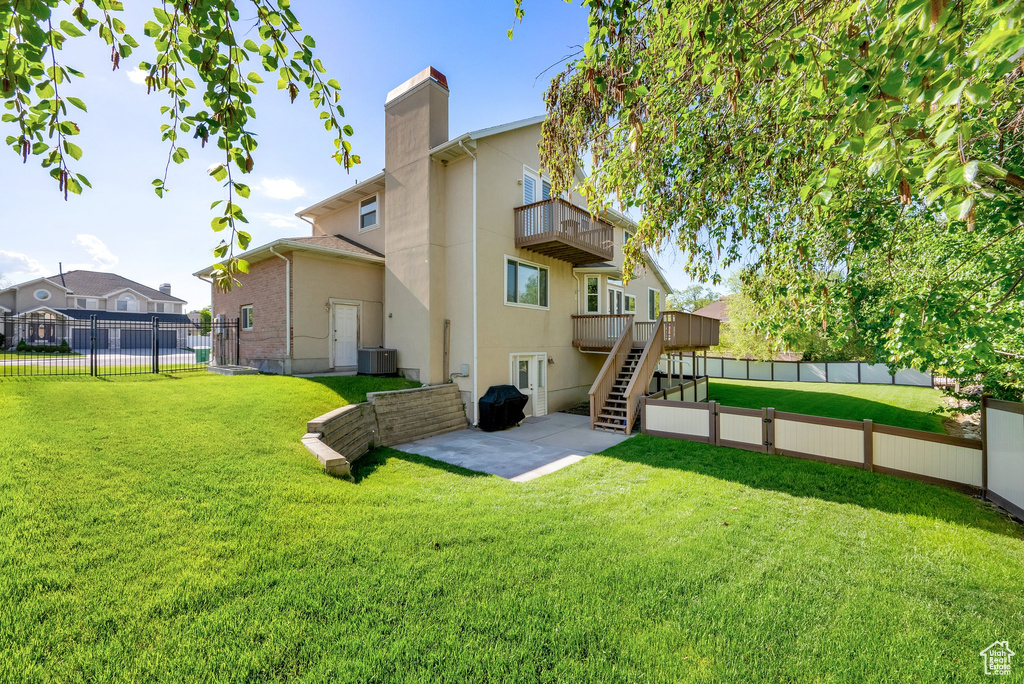 Back of house with a balcony, a patio area, stairway, stucco siding, and a chimney