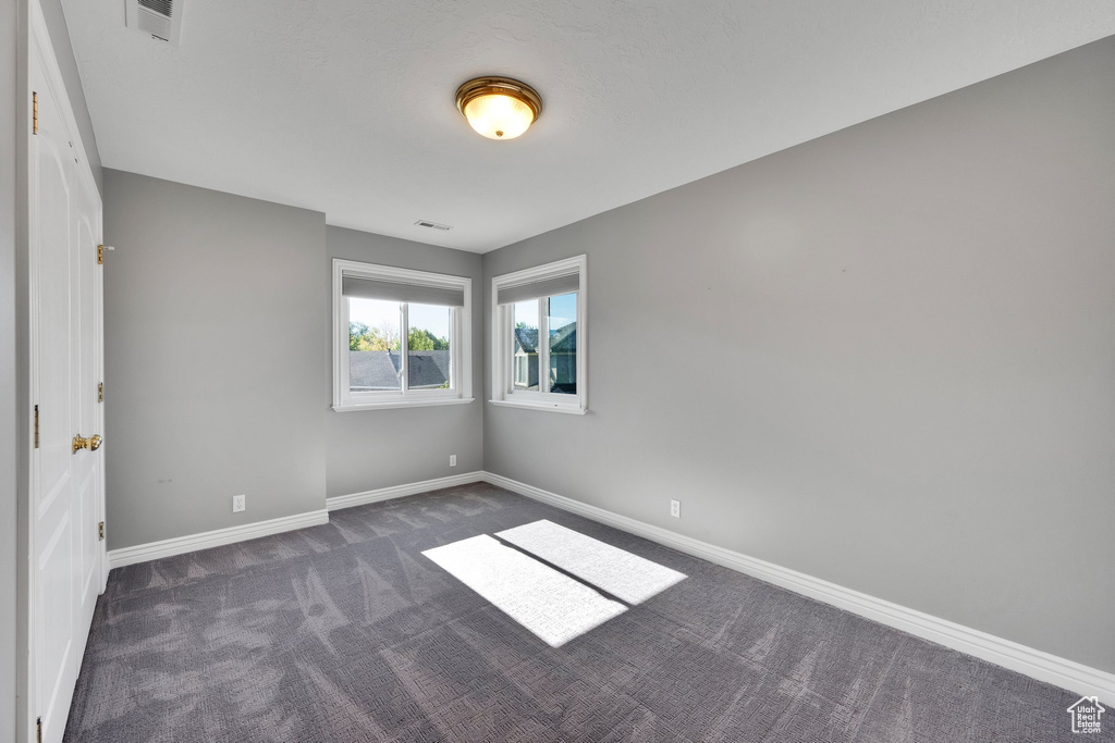 Empty room featuring dark carpet and baseboards