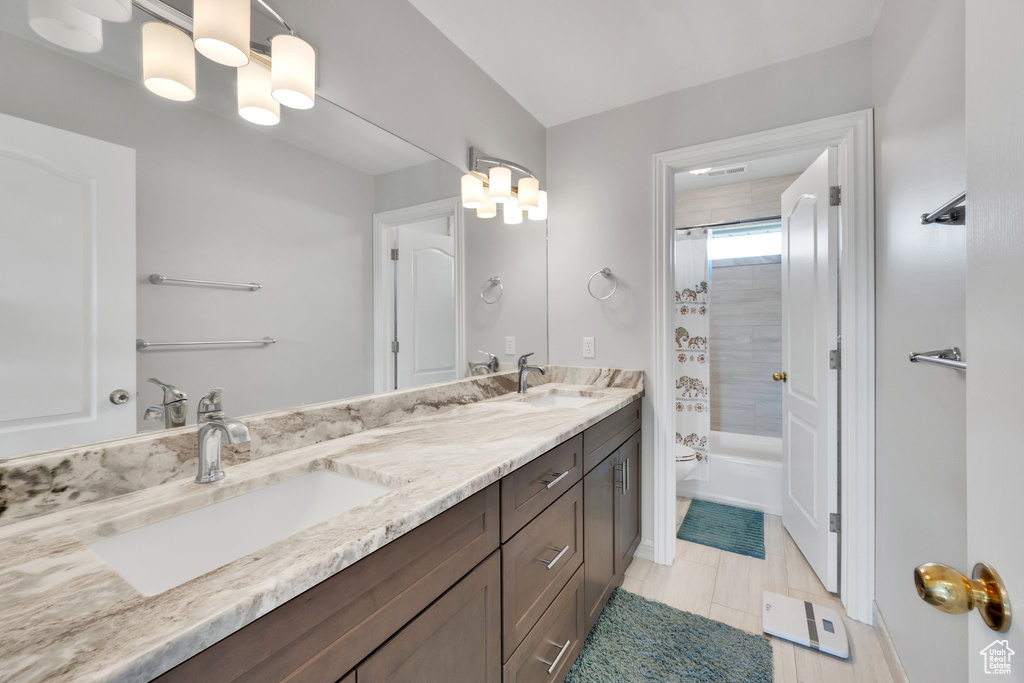 Bathroom featuring toilet, double vanity, and shower / bath combo