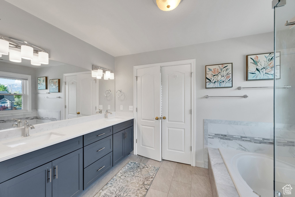 Full bathroom featuring a bath, double vanity, and tile patterned flooring