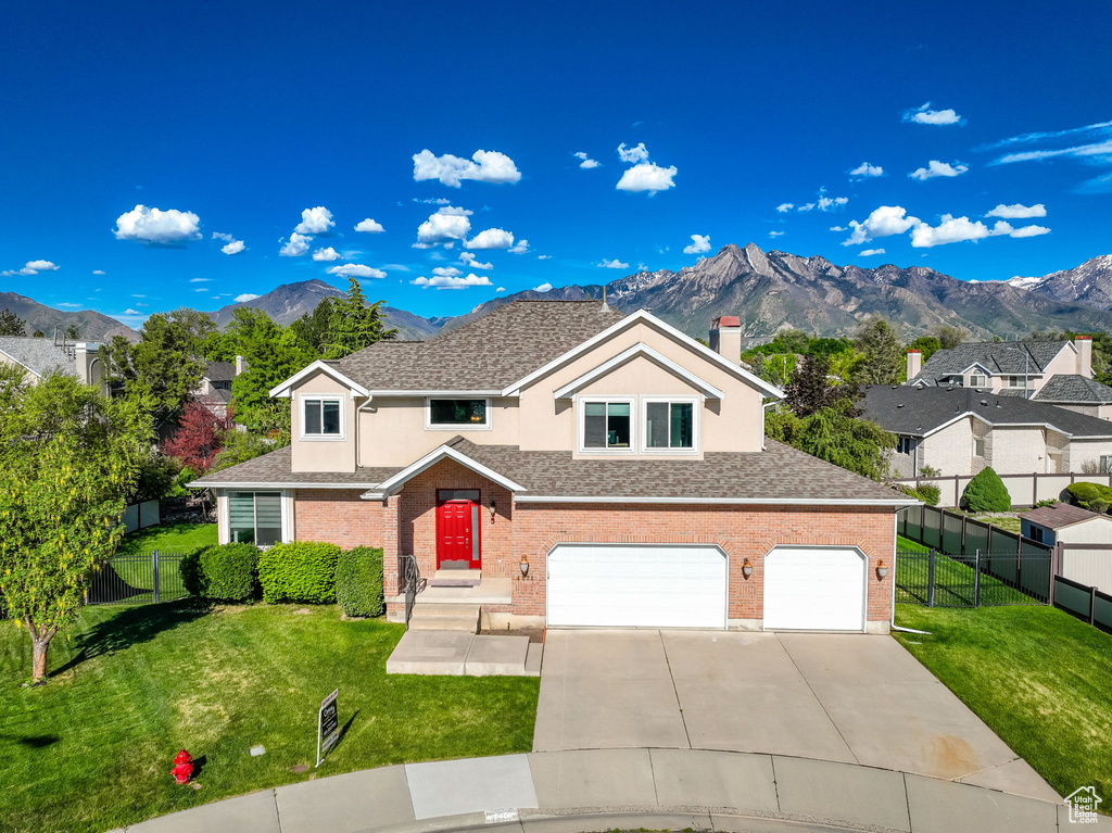 Traditional-style home featuring a garage, a mountain view, concrete driveway, a chimney, and brick siding
