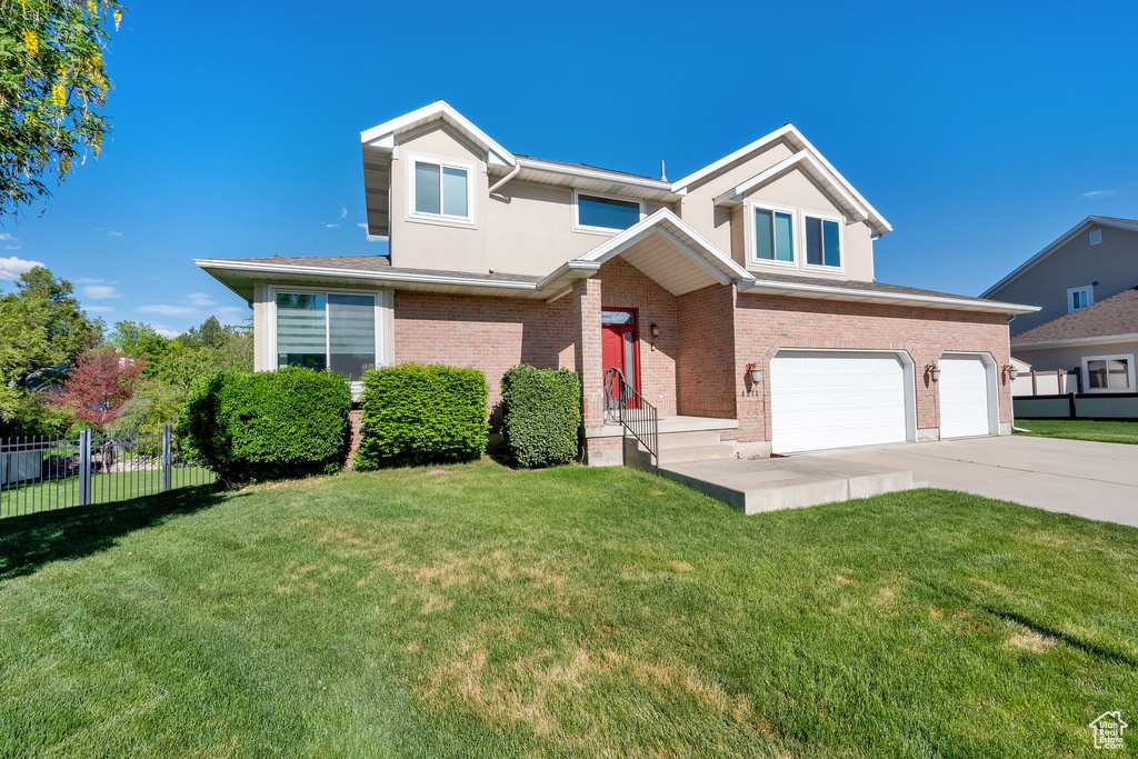 Traditional-style home with a garage, concrete driveway, brick siding, and stucco siding
