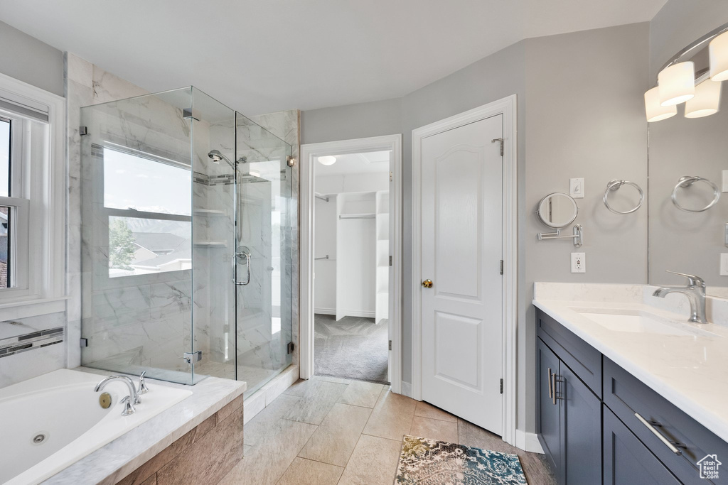 Bathroom featuring a whirlpool tub, vanity, a marble finish shower, and baseboards