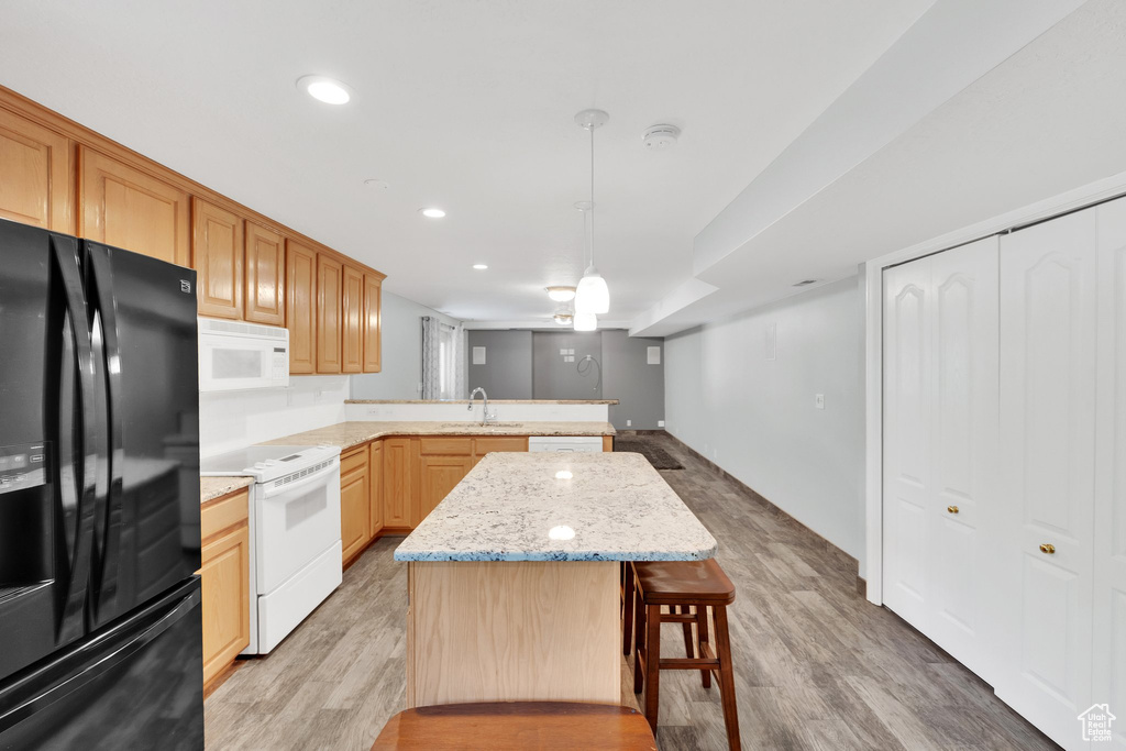 Kitchen featuring white appliances, a peninsula, a sink, light wood-style floors, and recessed lighting