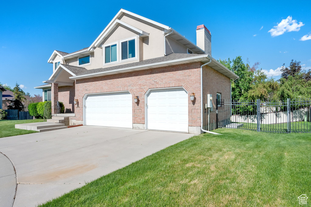 View of side of property with an attached garage, concrete driveway, a chimney, and brick siding