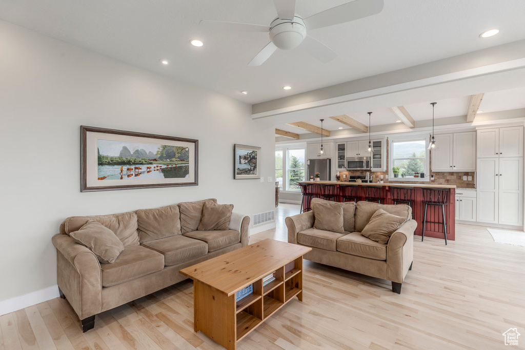 Living area featuring light wood finished floors, recessed lighting, beamed ceiling, baseboards, and a ceiling fan