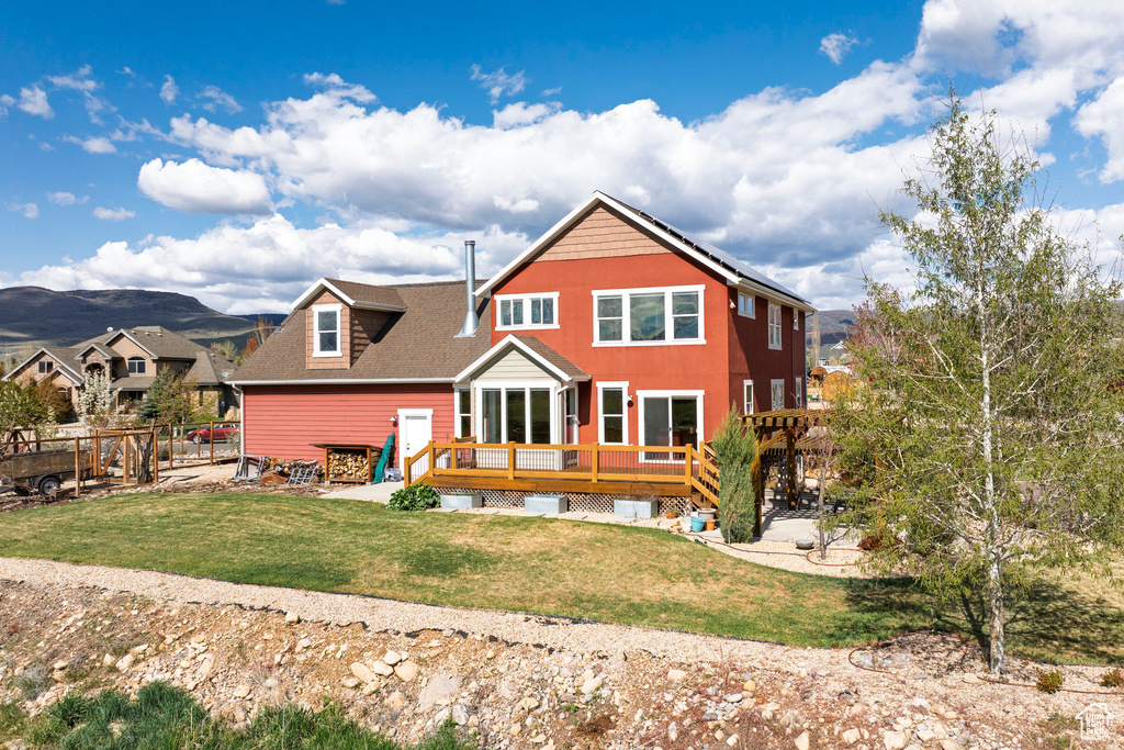 Rear view of house with a deck with mountain view and roof with shingles