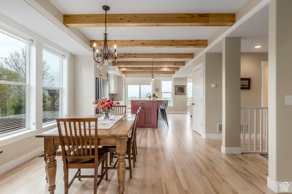 Dining area featuring light wood-style floors, beam ceiling, a chandelier, baseboards, and recessed lighting