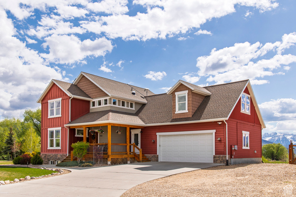 View of front of house with a porch, concrete driveway, board and batten siding, stone siding, and a shingled roof