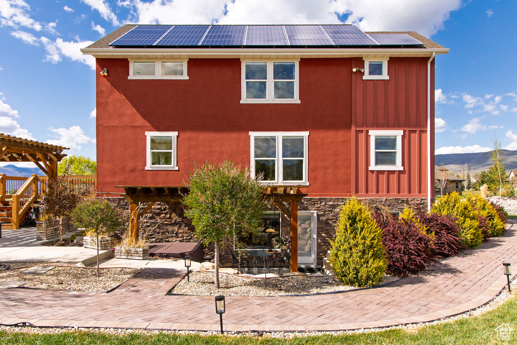Rear view of house featuring a patio area, board and batten siding, and solar panels