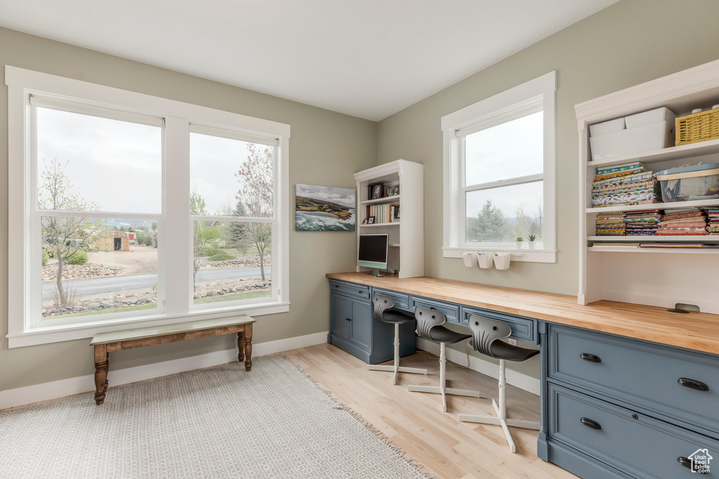 Office with built in desk, light wood-style flooring, and baseboards