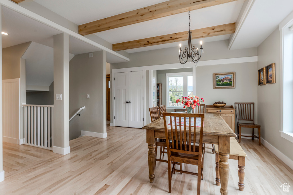 Dining room with light wood-style floors, a chandelier, baseboards, and beam ceiling
