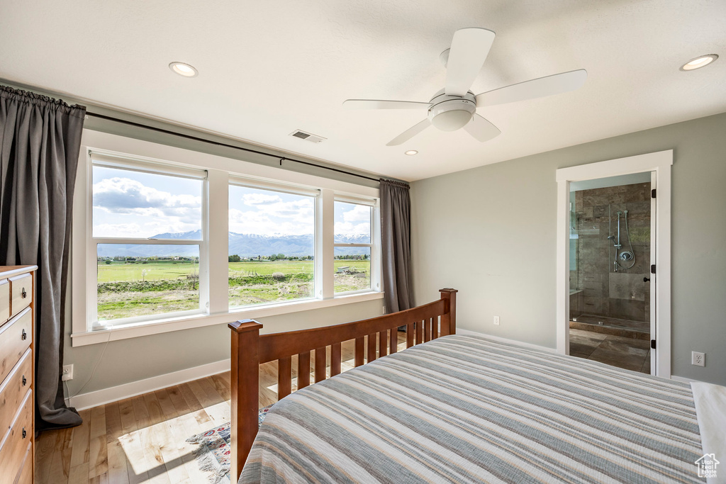 Bedroom featuring multiple windows, baseboards, light wood-style floors, recessed lighting, and connected bathroom