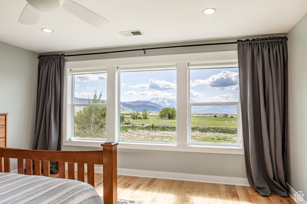 Bedroom featuring multiple windows, wood finished floors, recessed lighting, baseboards, and a mountain view