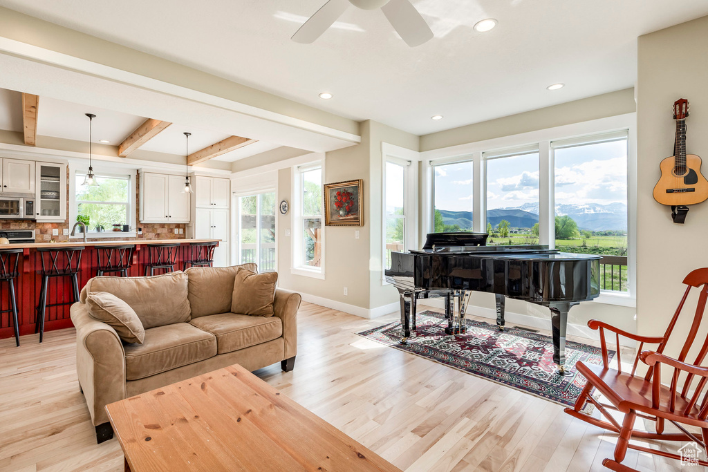 Living room featuring light wood-style flooring, beam ceiling, baseboards, recessed lighting, and ceiling fan