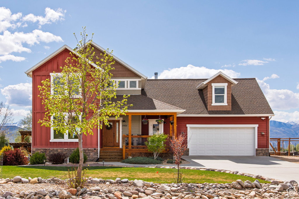 Craftsman-style house featuring a porch, stone siding, concrete driveway, board and batten siding, and a shingled roof