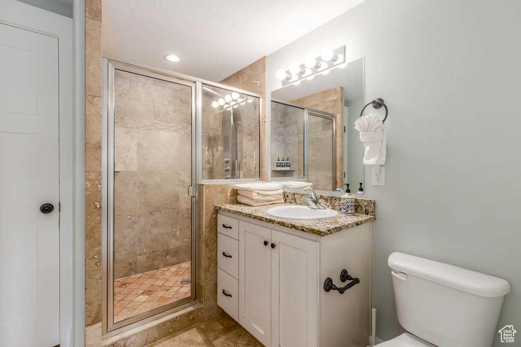 Bathroom with a shower stall, vanity, and toilet