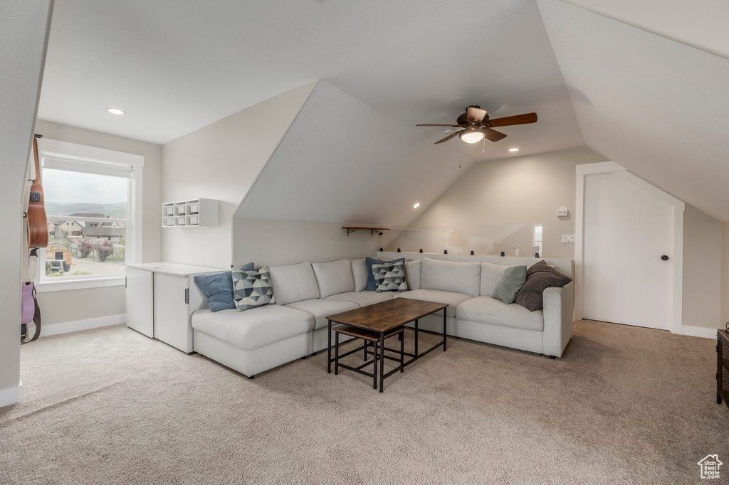 Carpeted living room with lofted ceiling, ceiling fan, and recessed lighting