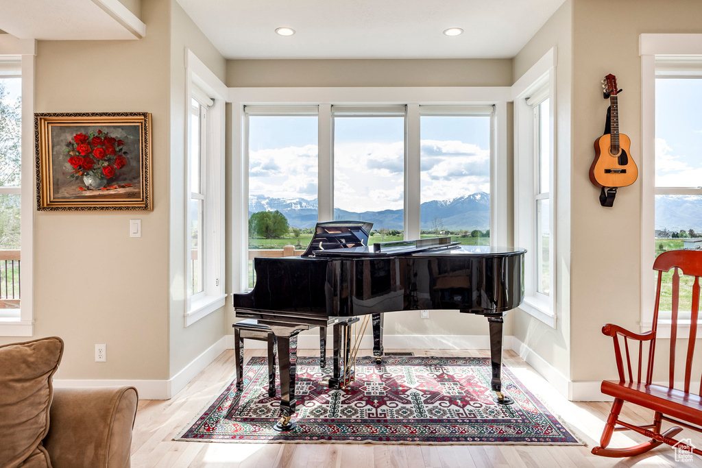 Living area featuring baseboards, light wood-type flooring, a mountain view, and recessed lighting