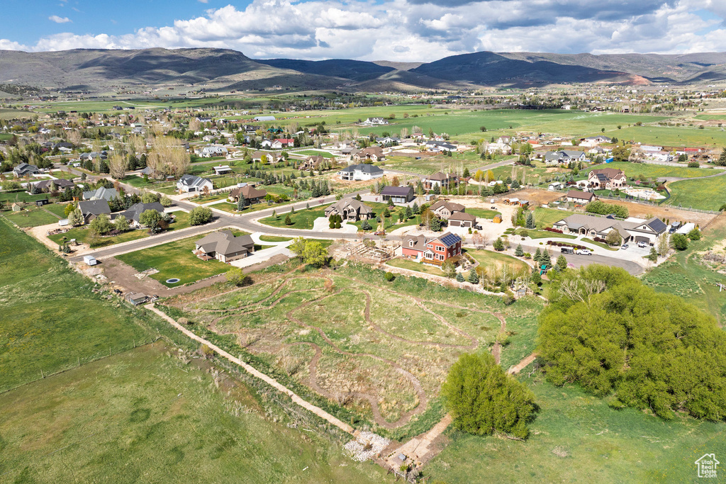 Aerial view of property and surrounding area featuring a mountainous background and nearby suburban area