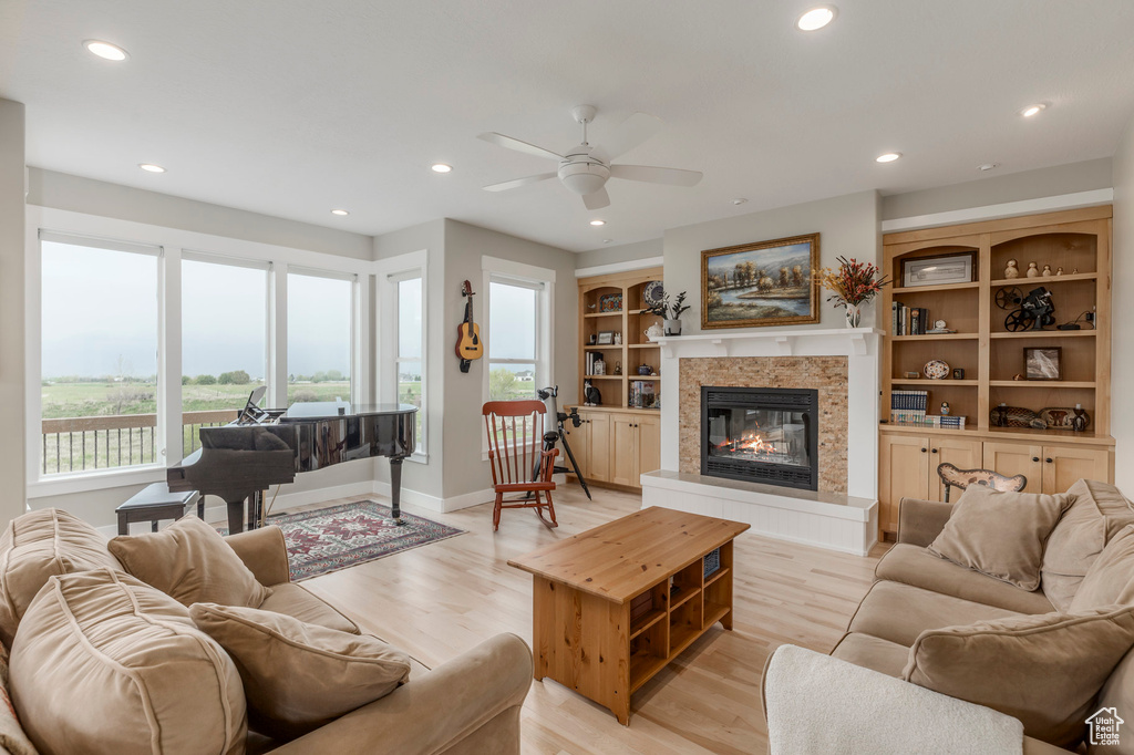 Living area featuring plenty of natural light, ceiling fan, a glass covered fireplace, recessed lighting, and light wood-type flooring