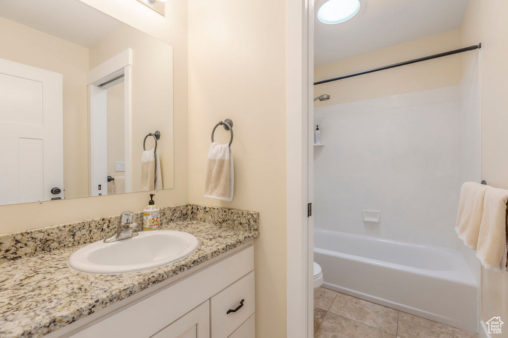 Bathroom featuring toilet, vanity, tile patterned flooring, and tub / shower combination
