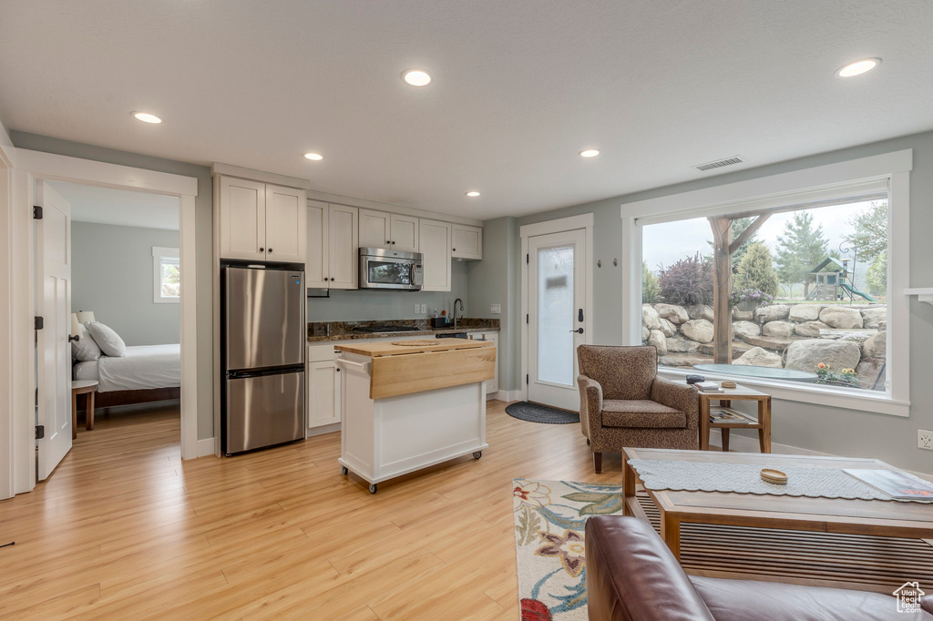 Kitchen with appliances with stainless steel finishes, wood counters, light wood-style flooring, recessed lighting, and a kitchen island