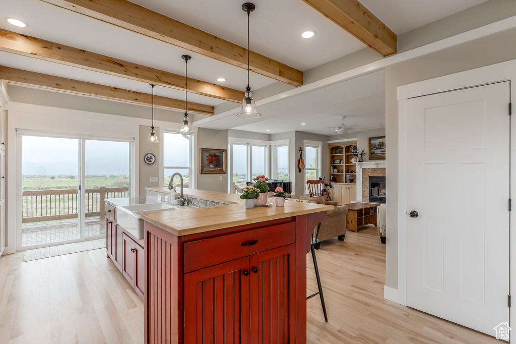 Kitchen featuring a sink, beam ceiling, a breakfast bar area, light wood-type flooring, and pendant lighting