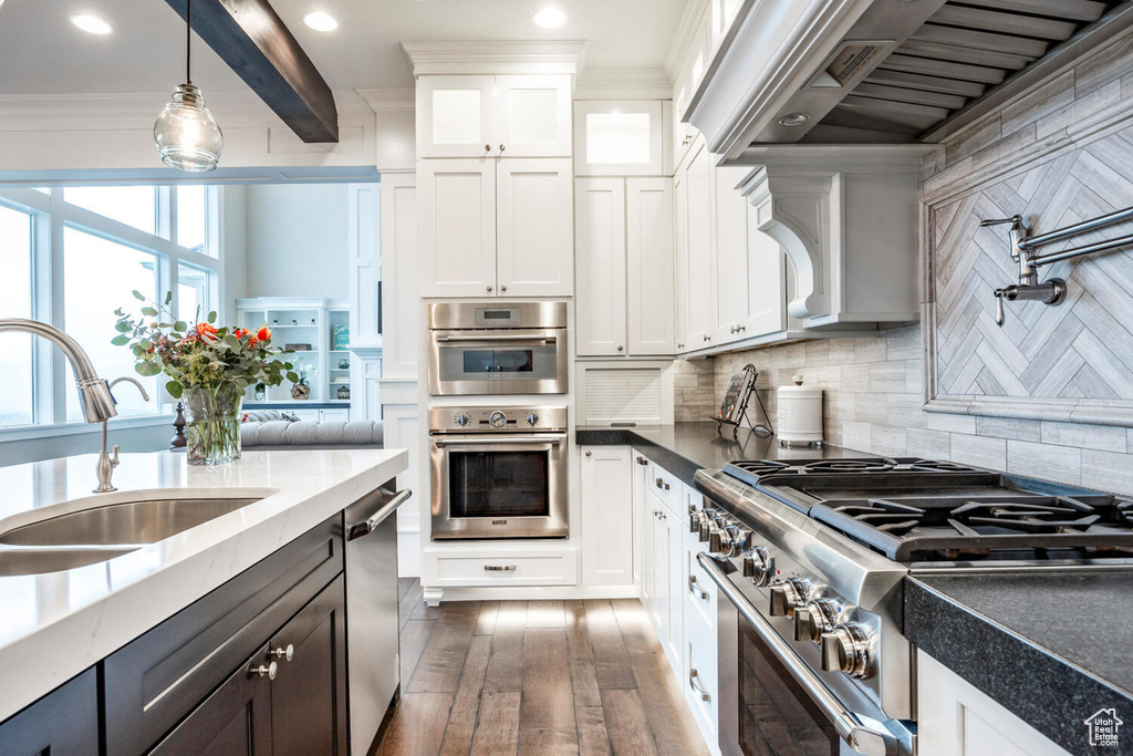 Kitchen featuring stainless steel appliances, a sink, ventilation hood, white cabinetry, and ornamental molding