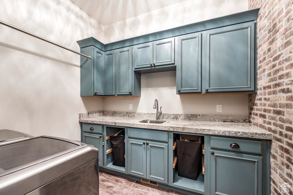 Laundry room with cabinet space, brick wall, and washer / dryer