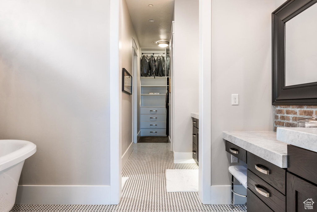 Bathroom with vanity, baseboards, and a spacious closet