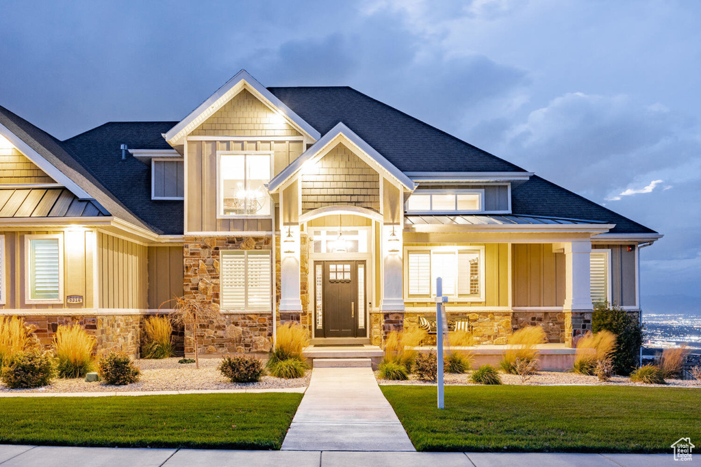 Craftsman inspired home with board and batten siding, a standing seam roof, stone siding, a shingled roof, and a front yard