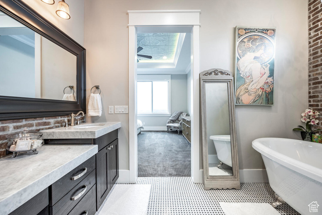 Ensuite bathroom with vanity, baseboards, a soaking tub, and tile patterned floors
