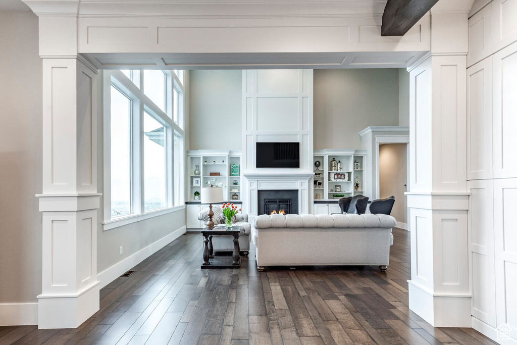 Living area featuring dark wood-style floors, baseboards, and a glass covered fireplace