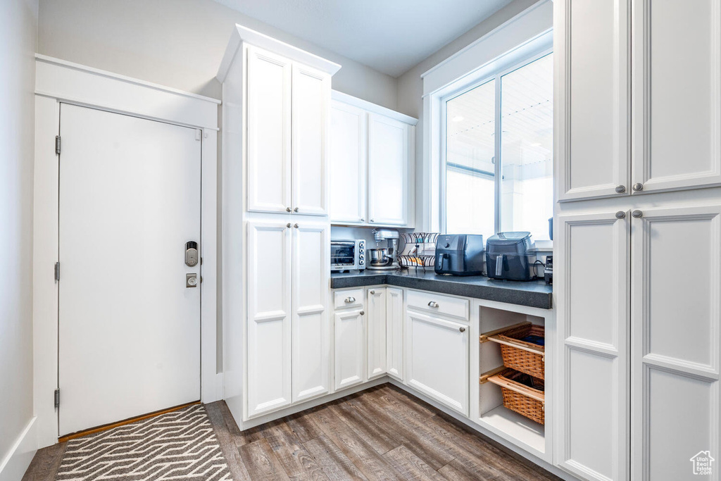 Kitchen with dark countertops, white cabinetry, wood finished floors, and open shelves