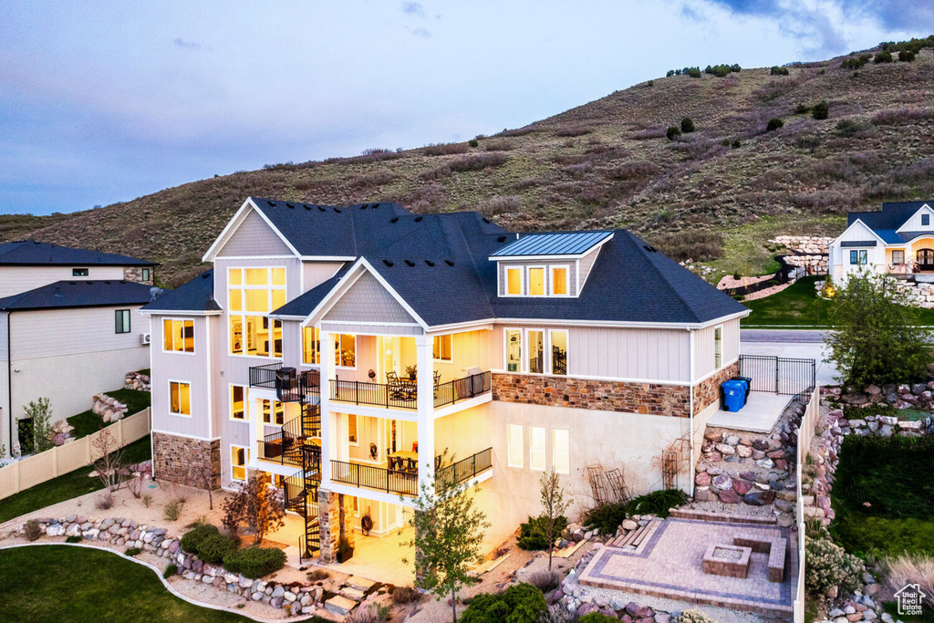 Rear view of house with a balcony, stairway, stone siding, and a fenced backyard