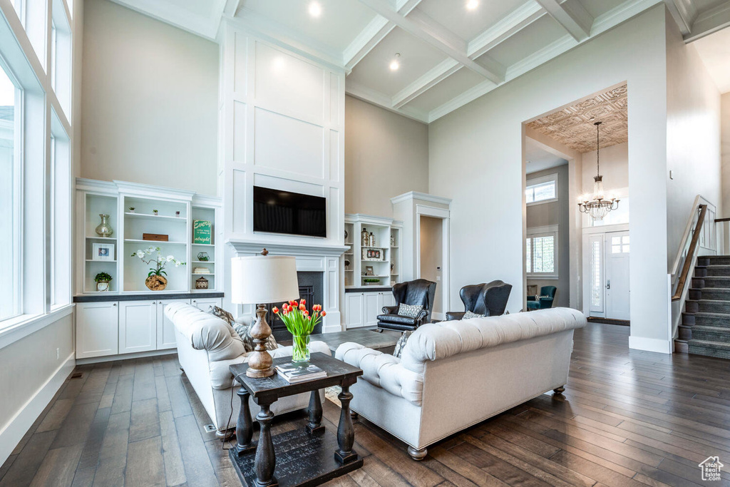 Living area with a high ceiling, dark wood-type flooring, stairs, a fireplace, and a chandelier
