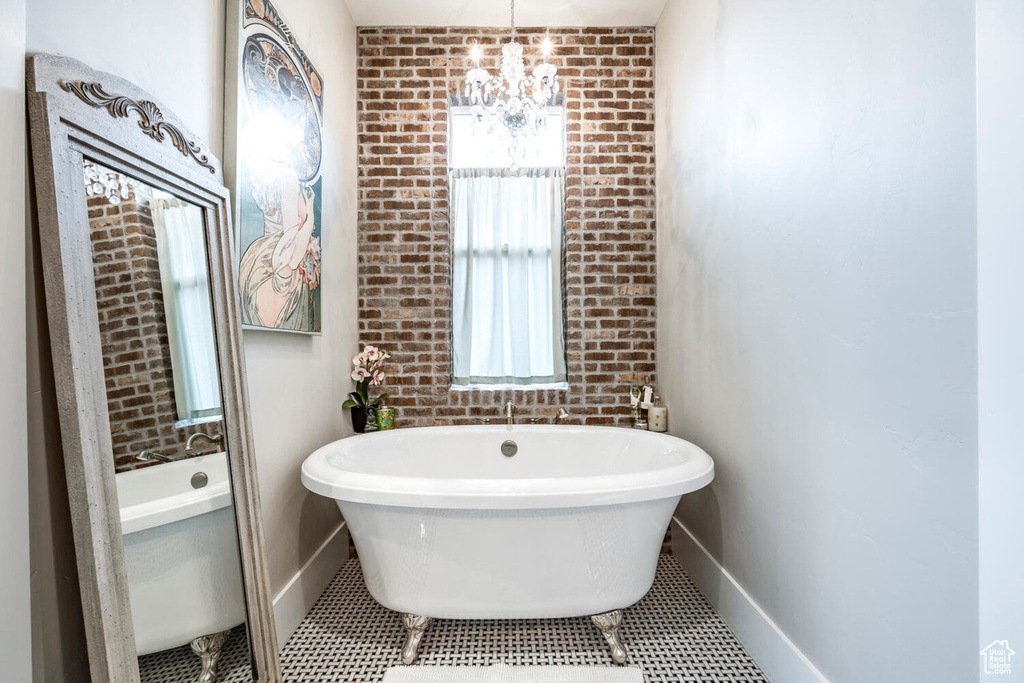 Full bathroom featuring a chandelier, a freestanding bath, and baseboards