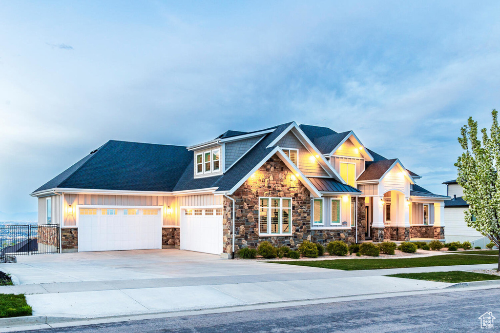 Craftsman house featuring stone siding, driveway, fence, and board and batten siding