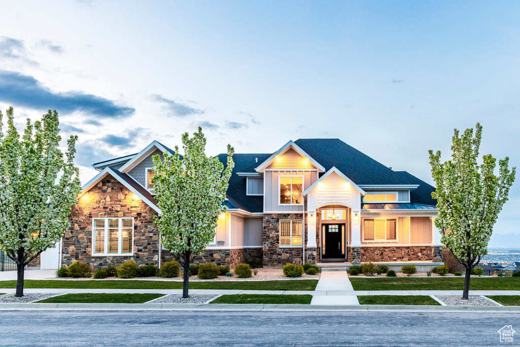 View of front facade with stone siding, a front yard, a standing seam roof, and metal roof