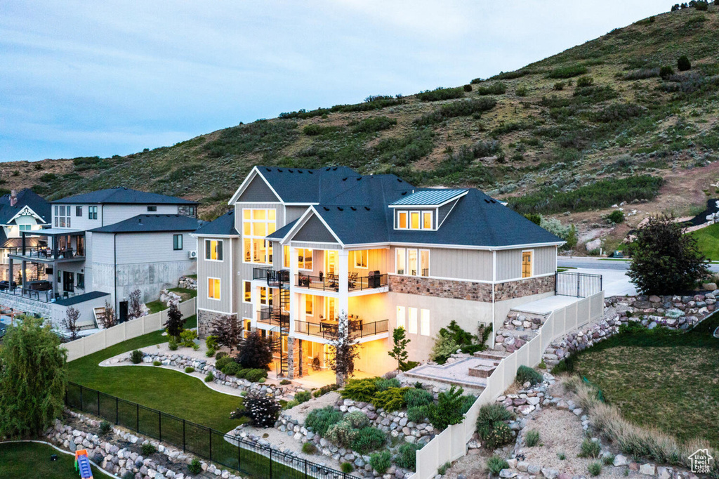 Back of property featuring stone siding, stairs, a mountain view, and a balcony
