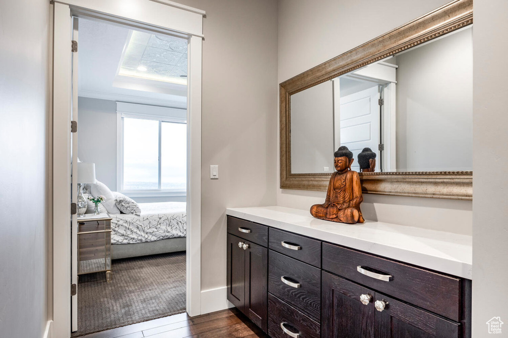 Bathroom with vanity, wood finished floors, baseboards, and ensuite bathroom