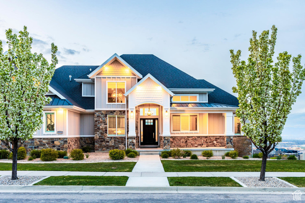 Craftsman house featuring a standing seam roof, board and batten siding, stone siding, metal roof, and a front yard